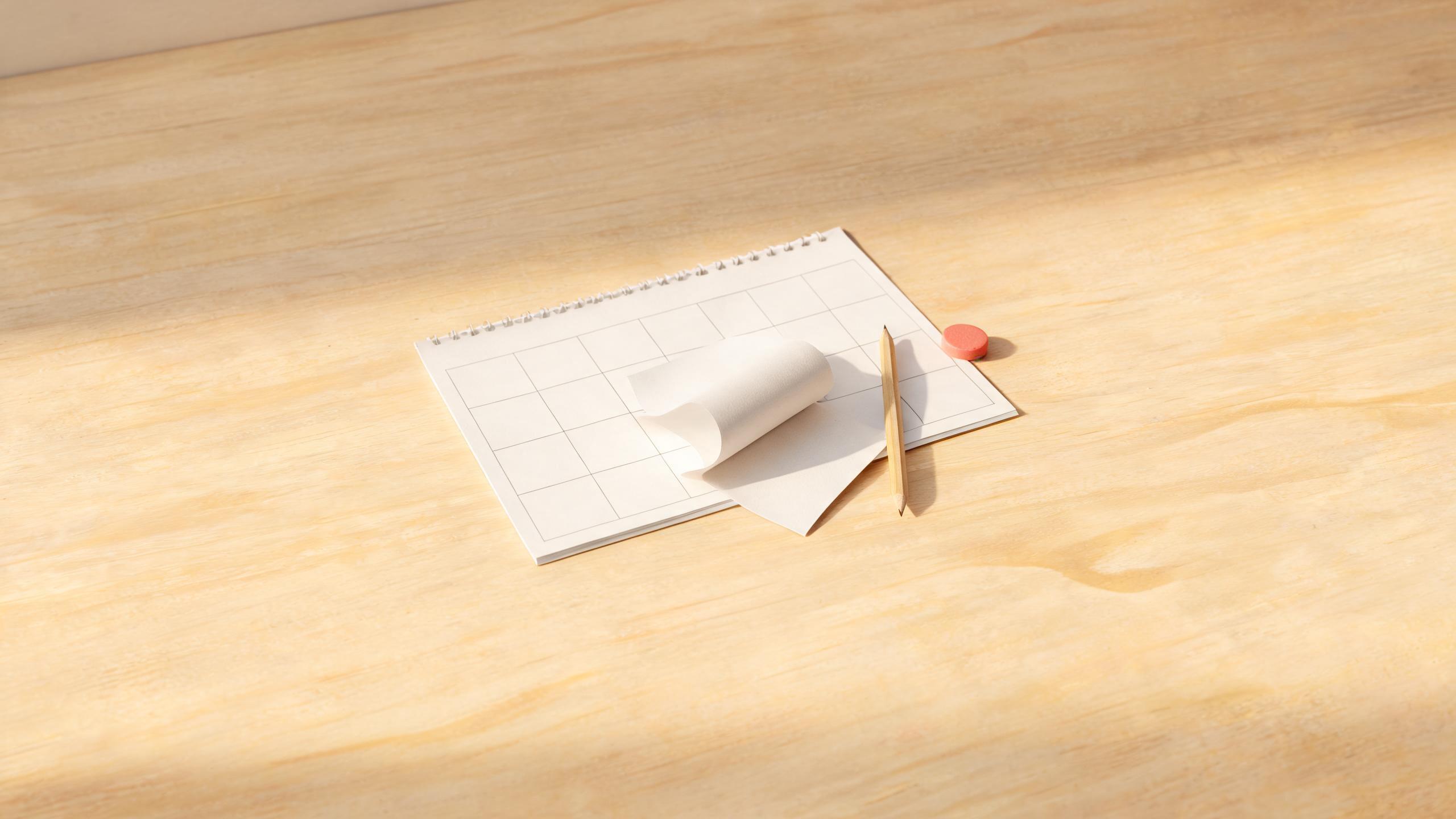 A short paper receipt resting on a blank calendar page, with a pencil beside it on a wooden desk